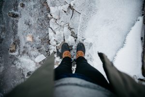 girl in snow with boots on standing up looking down self-care